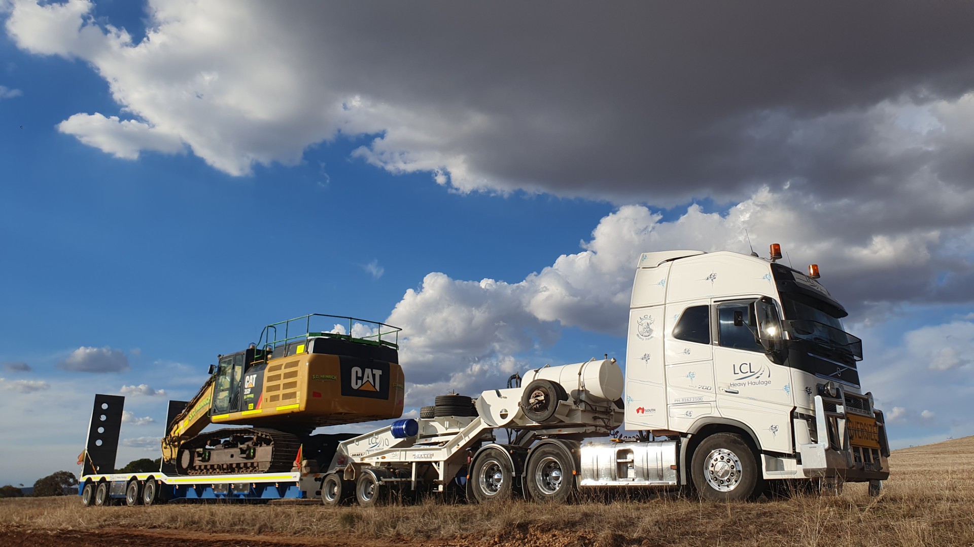 LCL Heavy Haulage multi-trailer road train truck driving on highway at sunset