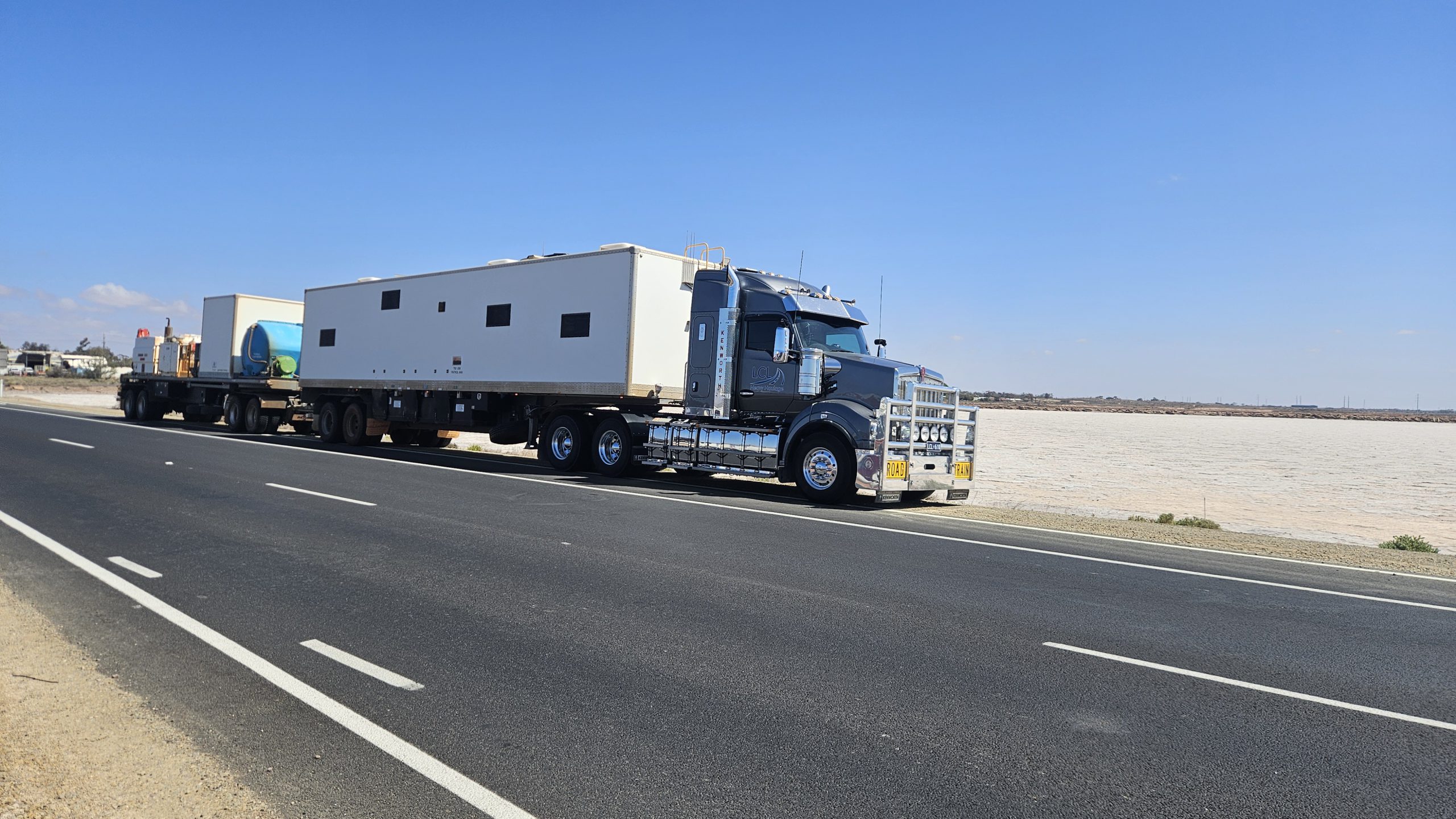 LCL Heavy Haulage multi-trailer road train truck driving on highway at sunset